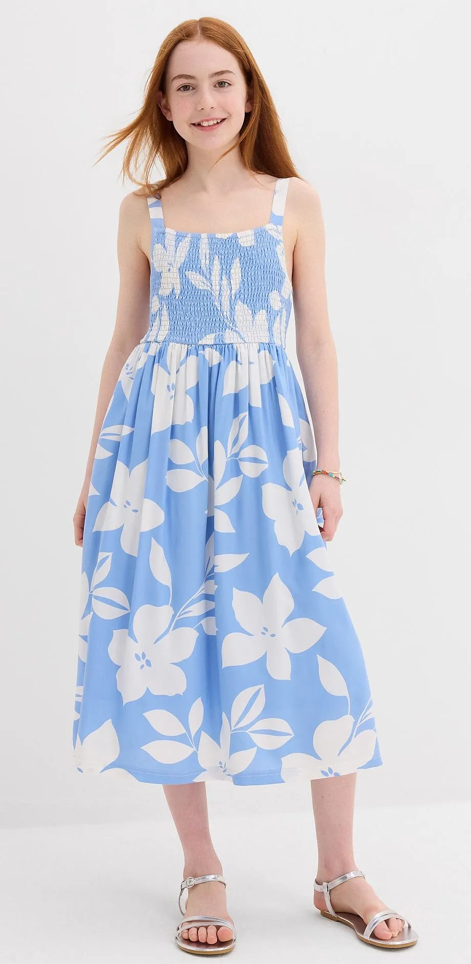 Una bambina indossa un vestitino estivo azzurro con fiori bianchi.
