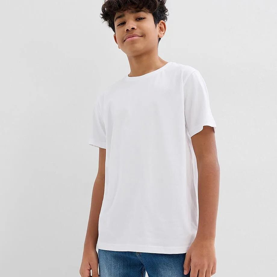 Un ragazzo indossa una semplice maglietta bianca e comodi jeans blu.
