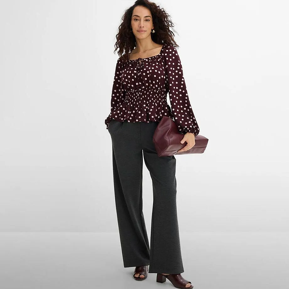 Blusa a pois, pantaloni larghi grigi e accessori bordeaux.