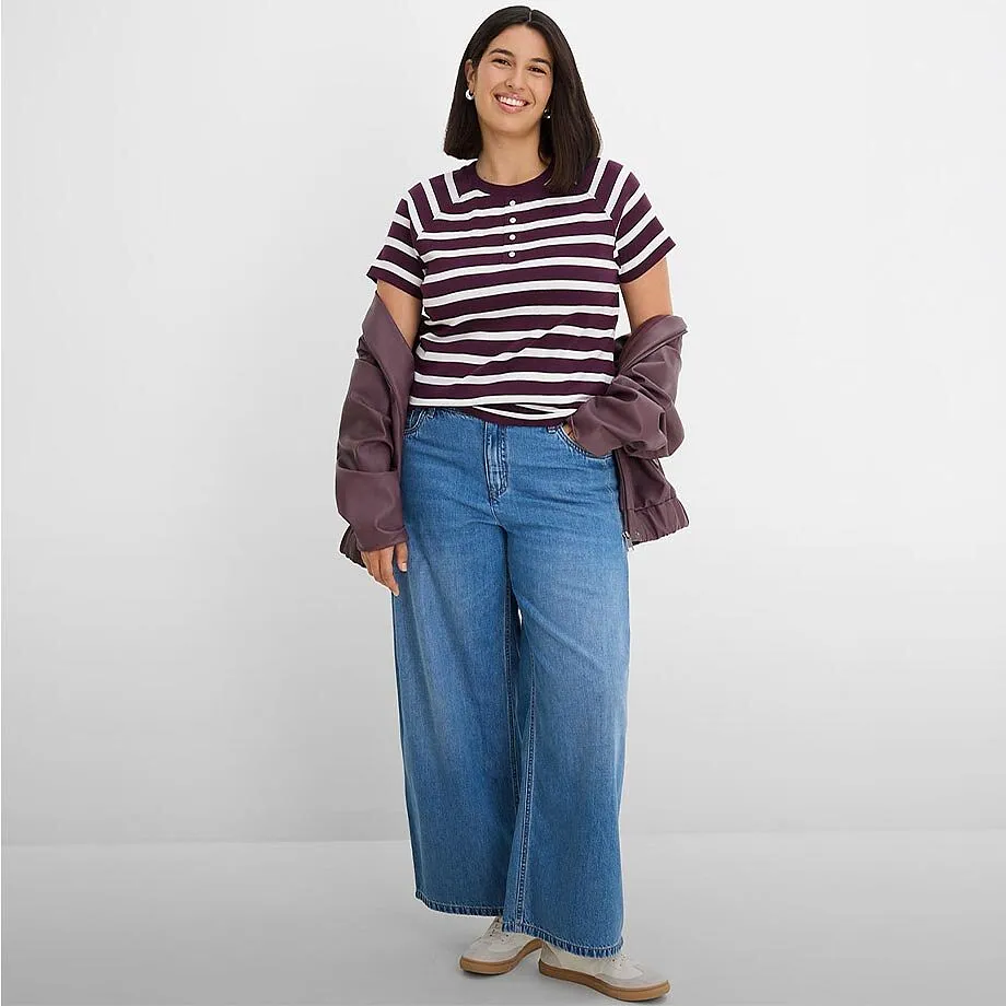 Una maglietta alla moda a righe, jeans larghi e una giacca casual.
