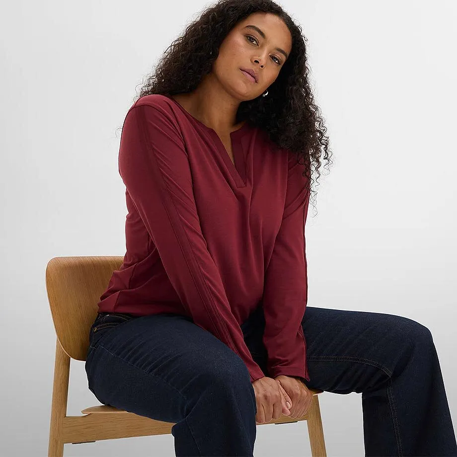 Maglia a maniche lunghe bordeaux con scollo a V e jeans blu scuro.