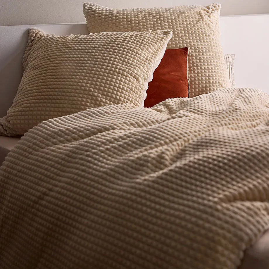I tessuti a trama regolare nei toni del crema conferiscono al letto un aspetto morbido e accogliente.