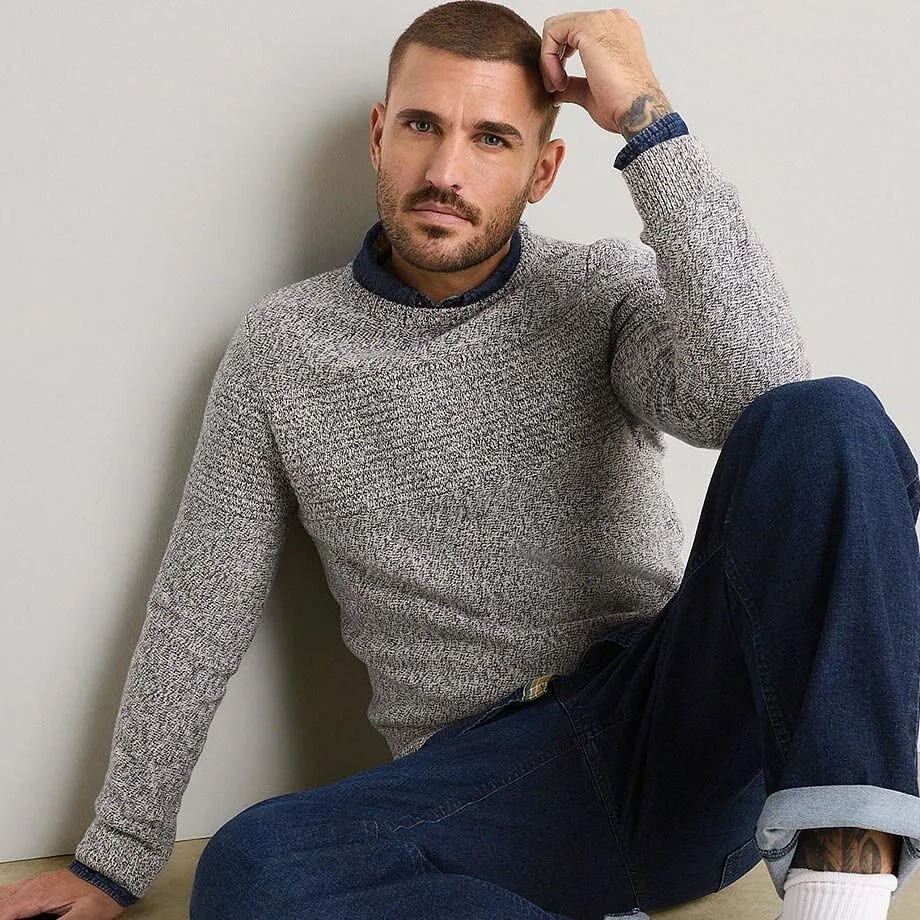 Maglione elegante a maglia grossa, con una camicia sotto, abbinato a jeans scuri.