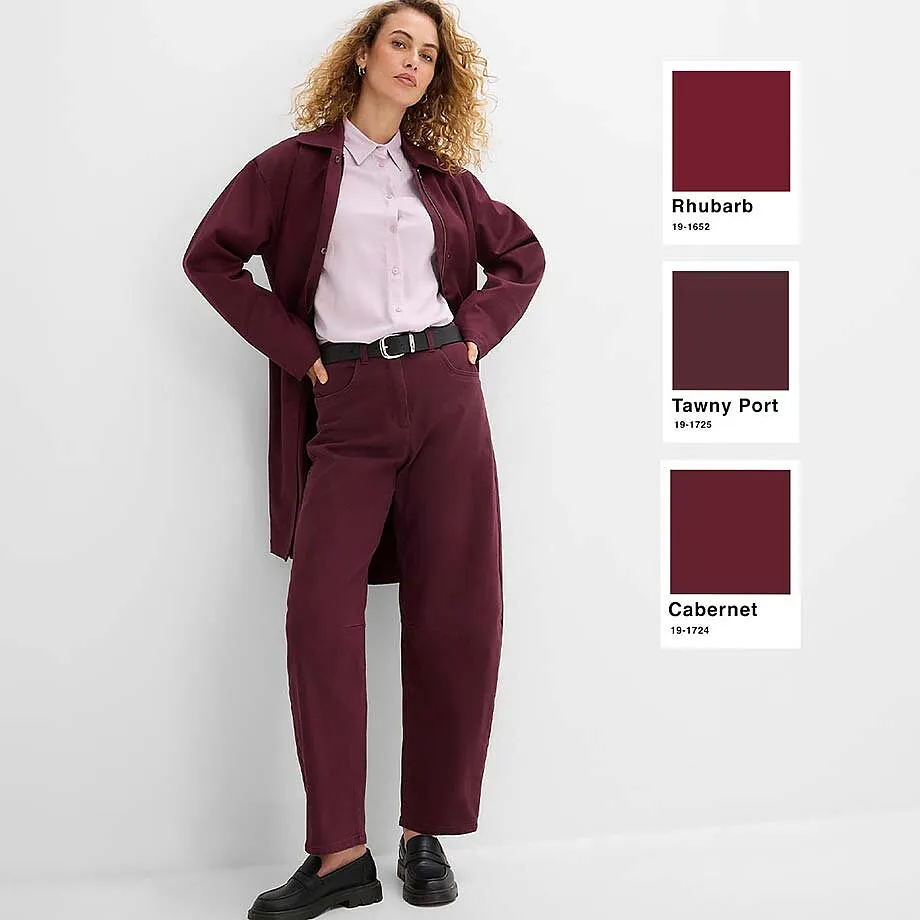 Pantaloni color bacca, camicetta rosa e giacca lunga color bacca.