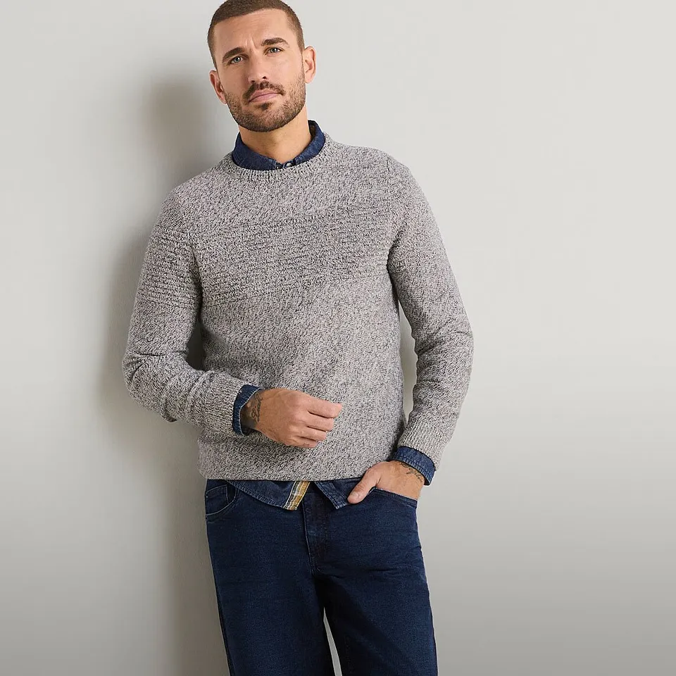 Maglione elegante a maglia grossa, con una camicia sotto, abbinato a jeans scuri.