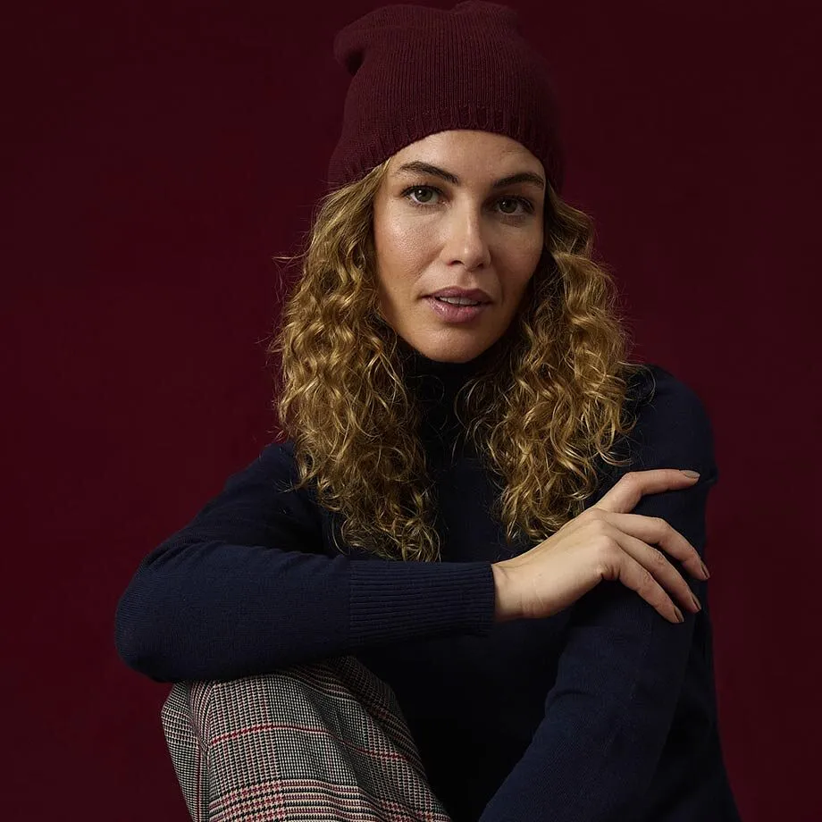 Un berretto di maglia rosso scuro, un maglione a collo alto blu scuro e un paio di pantaloni a quadri.