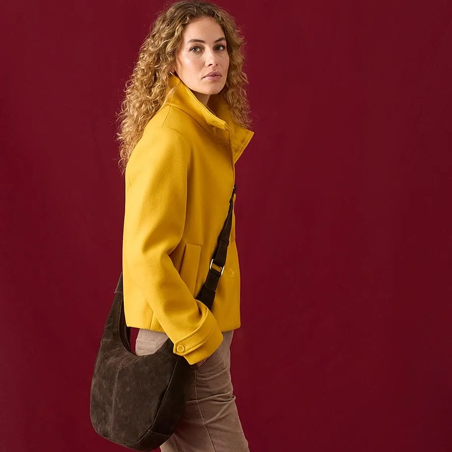 Una giacca gialla alla moda abbinata a pantaloni marroni e una borsa a tracolla dal look casual.