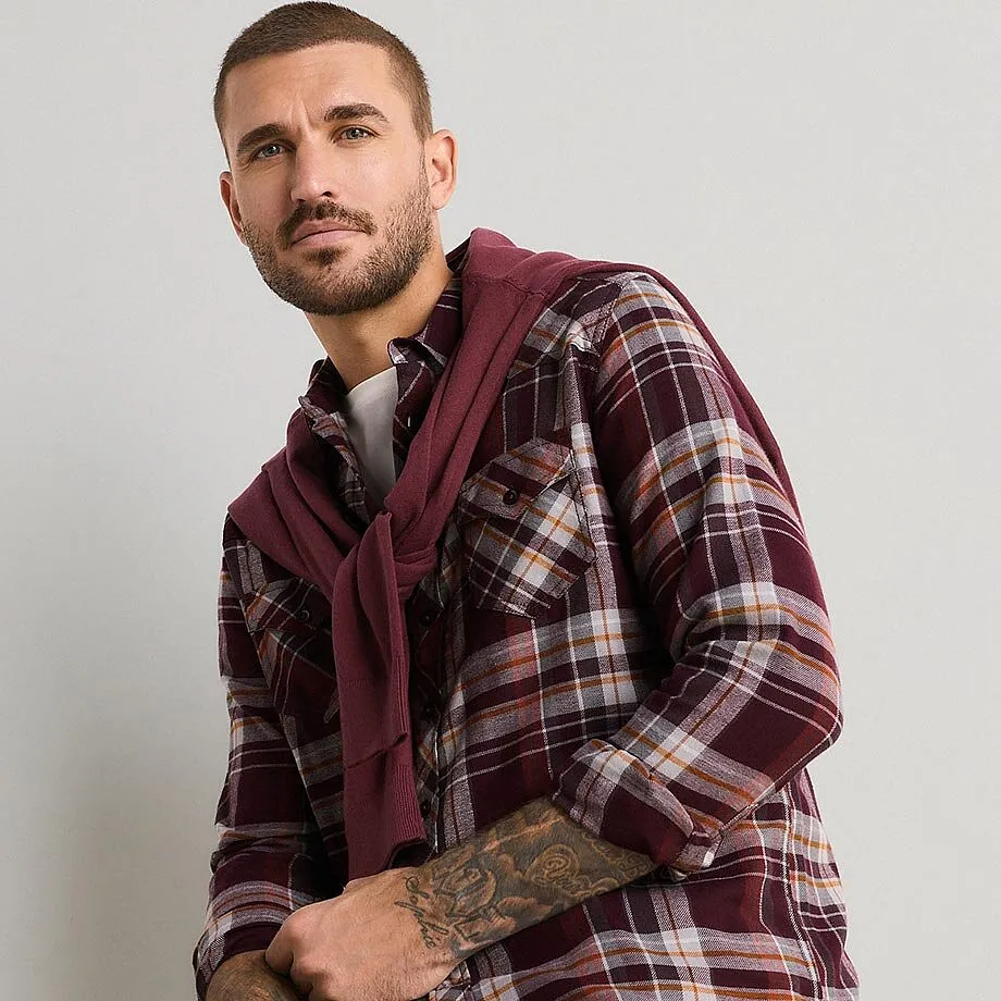 Elegante camicia a quadri e maglione bordeaux, indossato con disinvoltura sulle spalle.