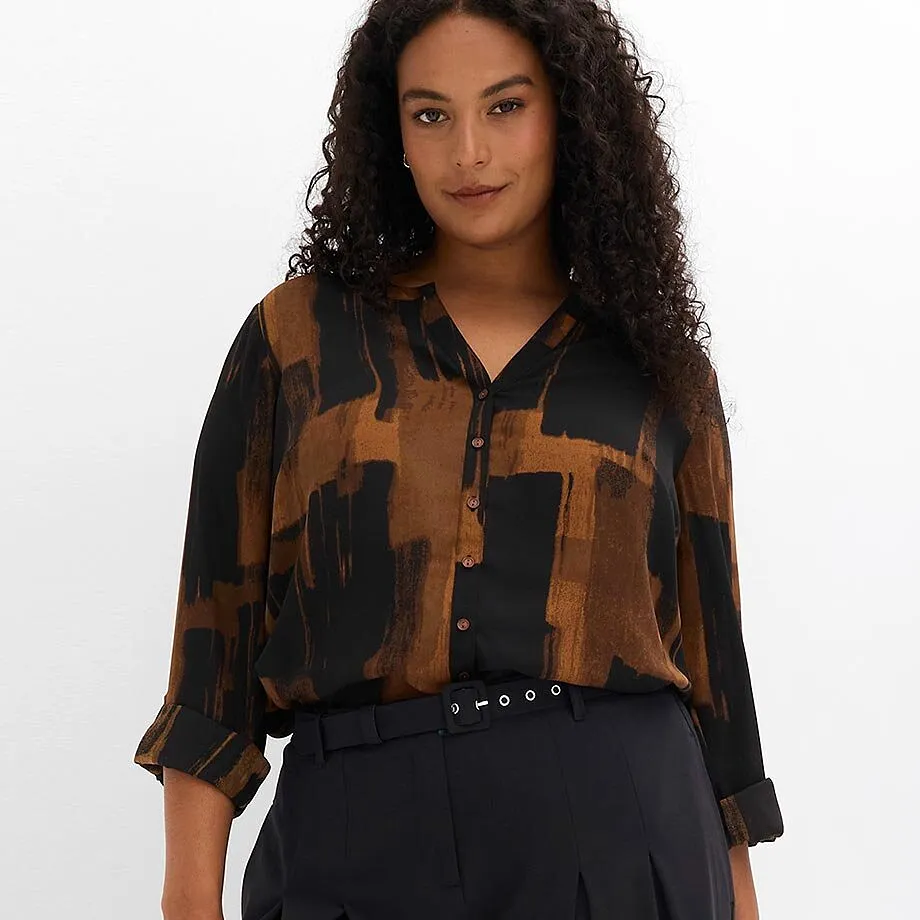 Camicetta alla moda nei toni del marrone e del nero, abbinata a pantaloni scuri e a una cintura elegante.