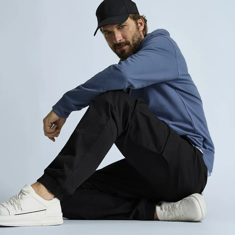 Look casual: berretto nero, felpa con cappuccio blu, comodi pantaloni cargo neri e sneakers bianche.
