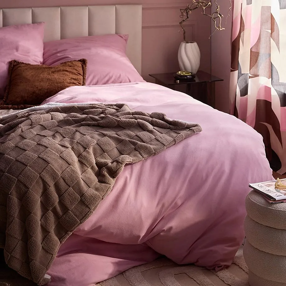 Biancheria da letto rosa e una morbida coperta marrone.