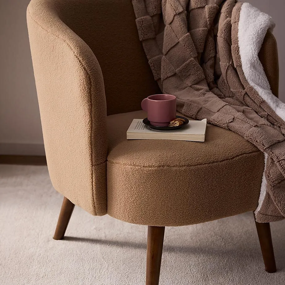 Comoda poltrona con una coperta marrone, un libro e una tazza.