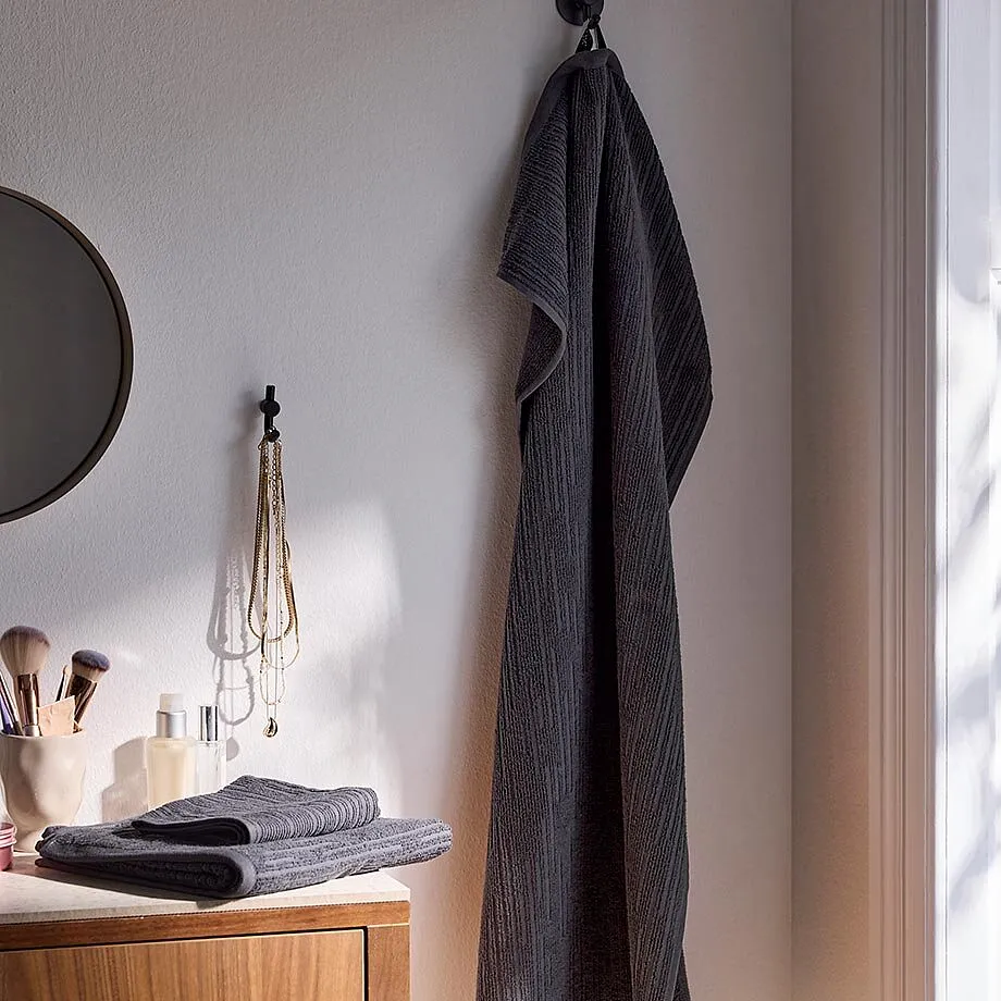 In bagno c'&egrave; un grande asciugamano grigio appeso.