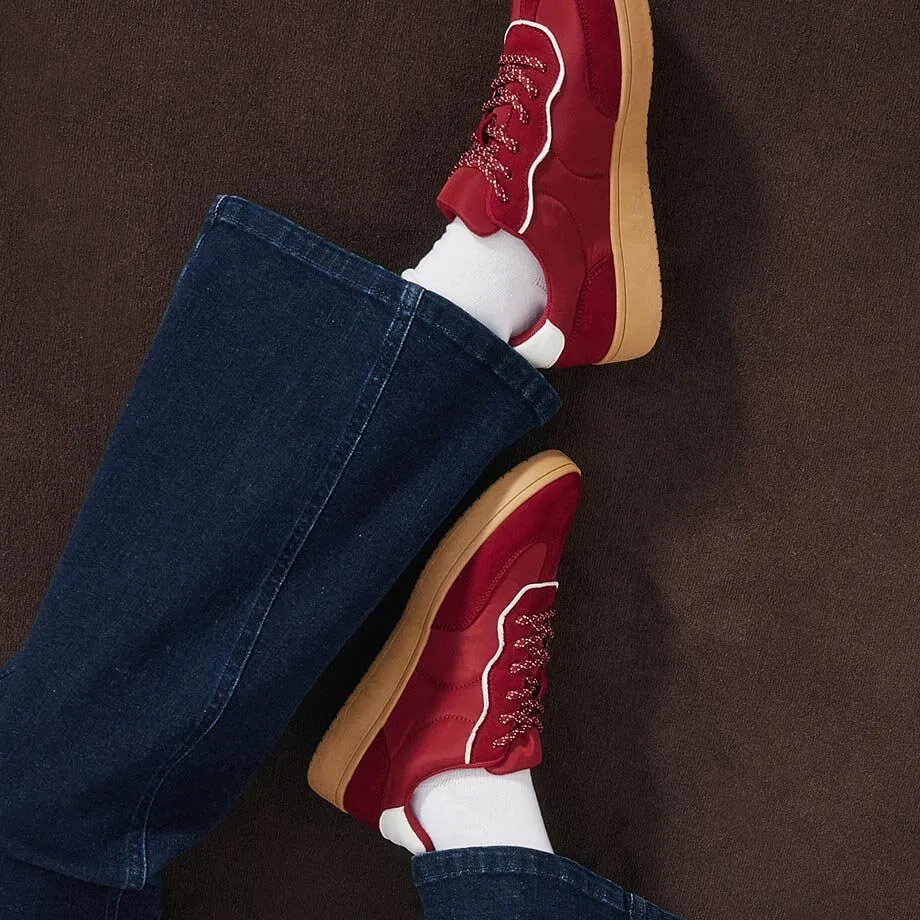 Sneaker rosse, calzini bianchi e jeans blu scuro.