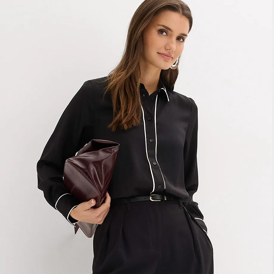 Camicia nera con colletto con profilo bianco, abbinata a pantaloni neri.