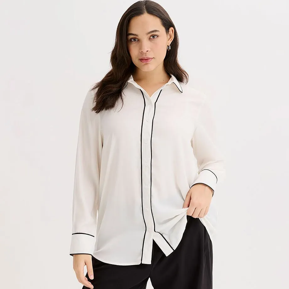 Camicetta bianca con bordino nero. Colletto classico e maniche lunghe.