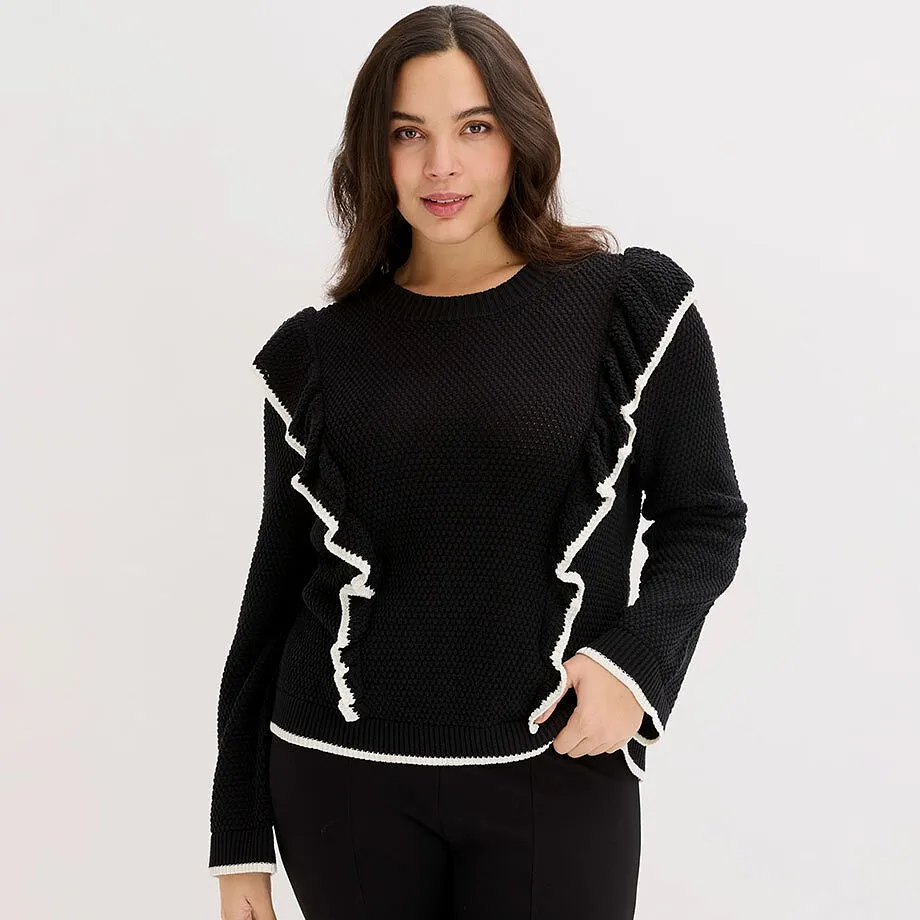 Maglione nero con volant bianchi sulle maniche e sul davanti.
