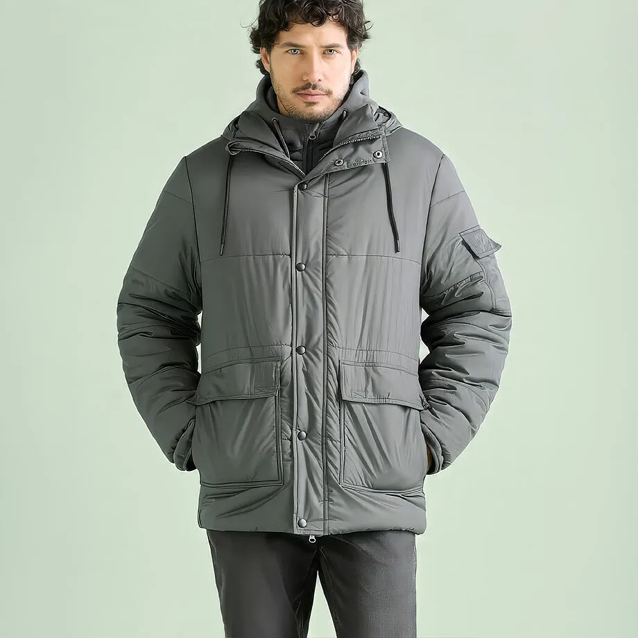 L'uomo indossa una giacca invernale grigia imbottita con cappuccio e pantaloni scuri.