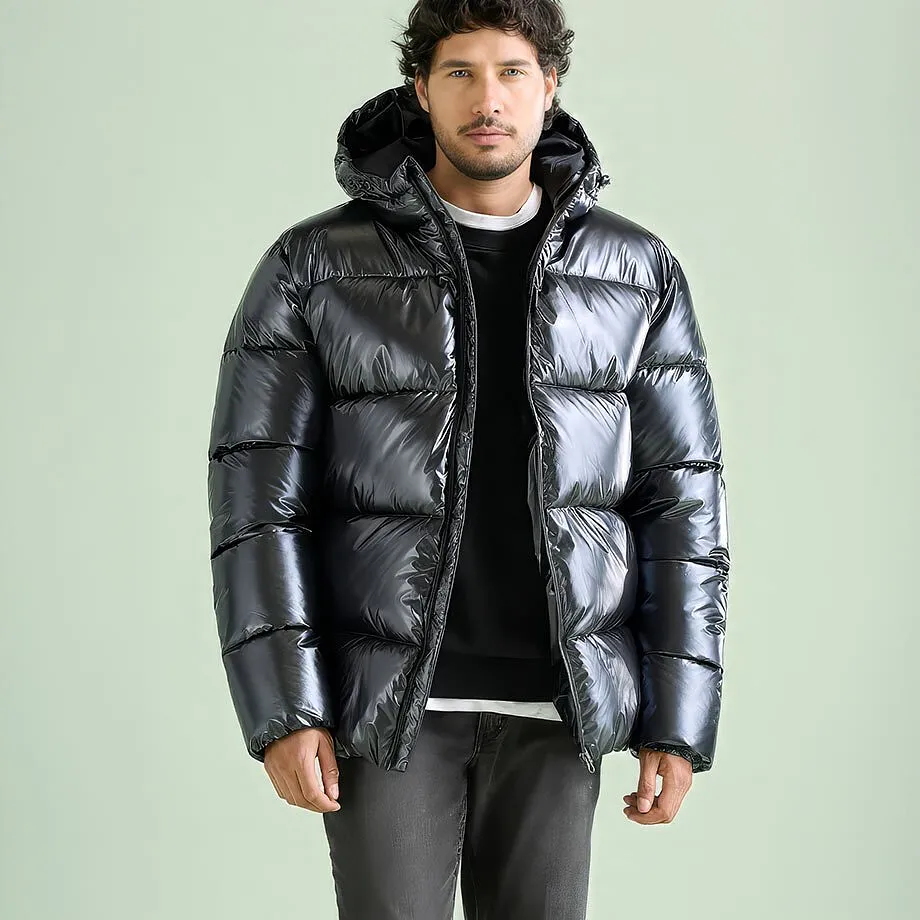 Giacca moderna nera lucida trapuntata con cappuccio, maglione nero e jeans grigi.