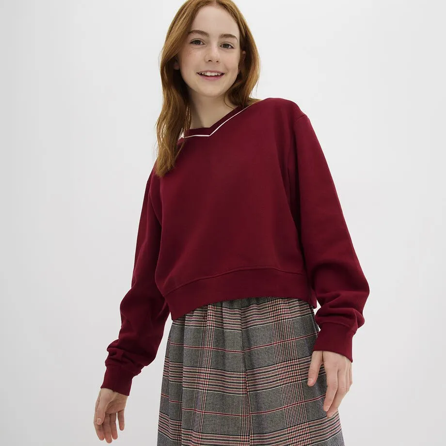 La ragazza indossa un maglione rosso scuro con scollo a V