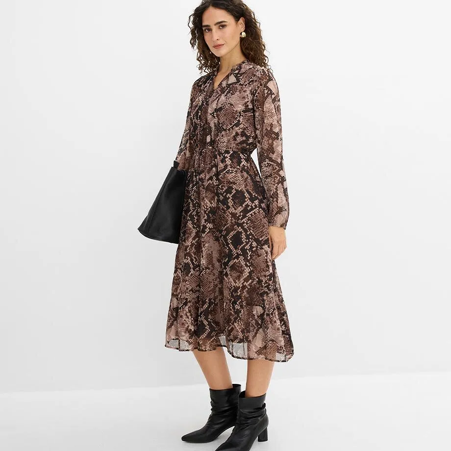 Elegante abito con motivo a serpente, stivaletti neri e borsa.