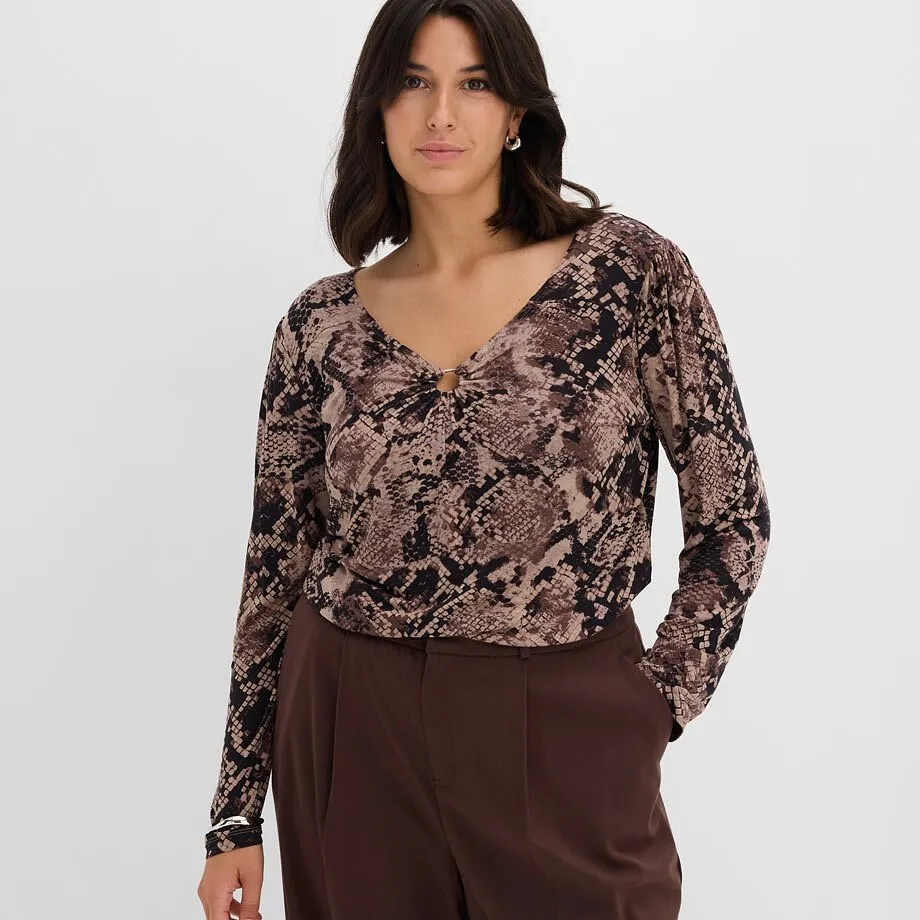  Top alla moda con motivo a serpente, scollo a V e dettaglio ad anello, abbinato a un paio di pantaloni marroni.