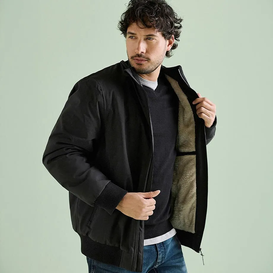 Giacca bomber nera con fodera morbida, maglione scuro e jeans.
