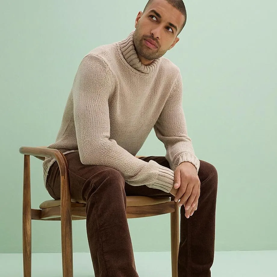 Un comodo maglione a collo alto beige e un paio di pantaloni di velluto a coste marroni.