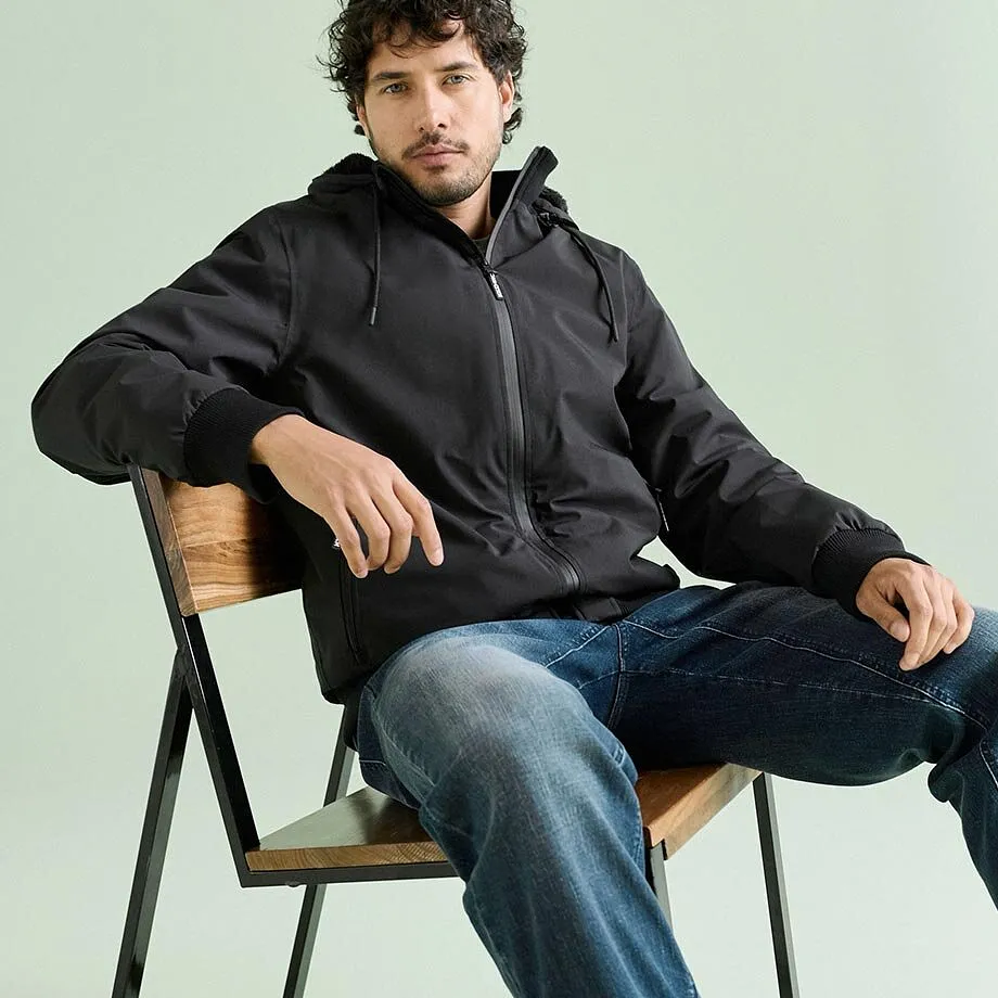 Indossa un'elegante giacca nera con cappuccio e comodi jeans blu.