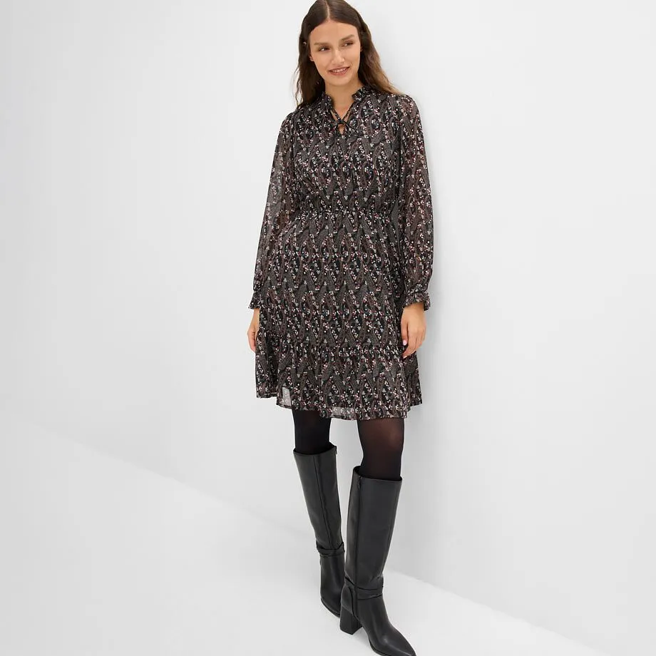 Un vestito alla moda con motivi, abbinato a collant neri e stivali al ginocchio.