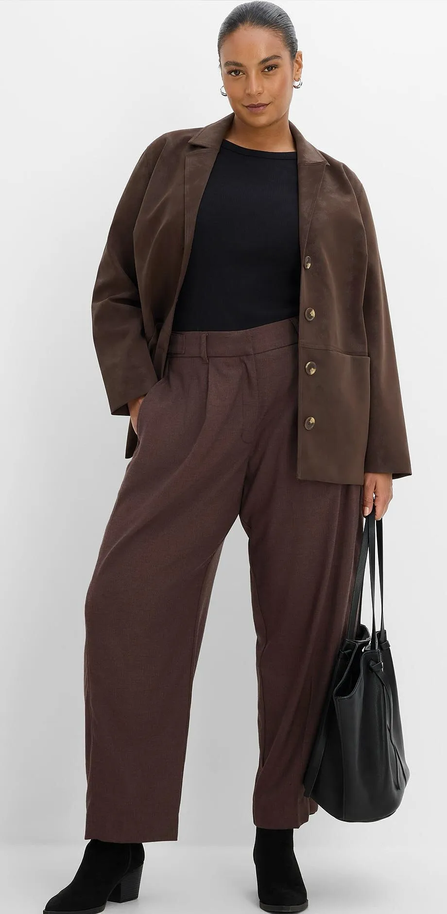 Blazer marrone, top nero, pantaloni larghi marroni, stivali neri e borsa.