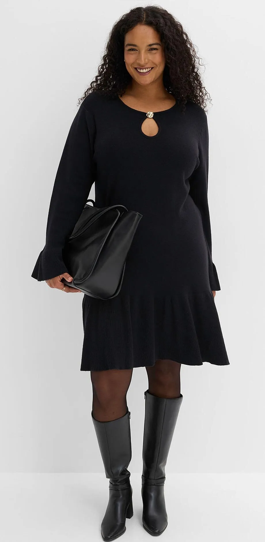 Elegante abito nero con scollo, abbinato a collant, stivali al ginocchio e borsetta.