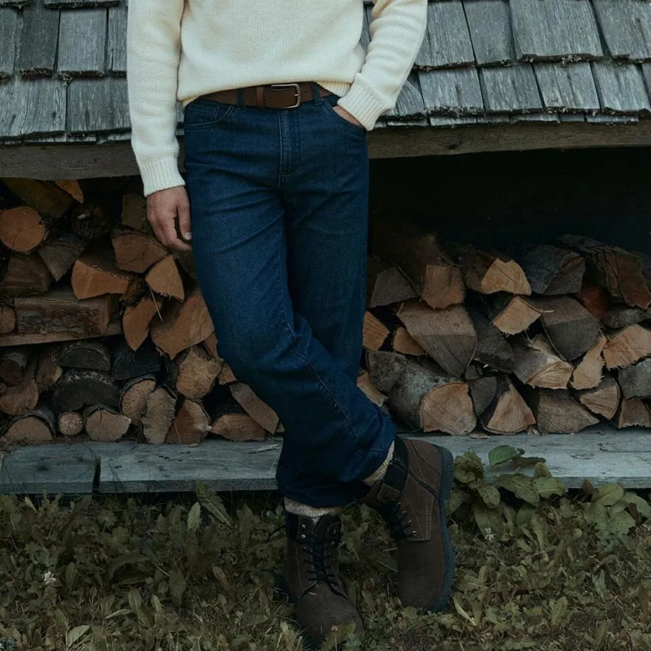 Maglione lavorato a maglia color crema, jeans, cintura marrone e robusti stivali invernali.