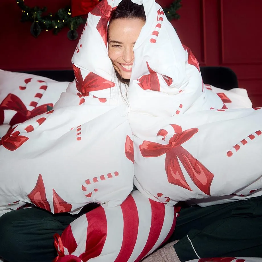 Indossa un pigiama ed &egrave; avvolta in una coperta festiva.