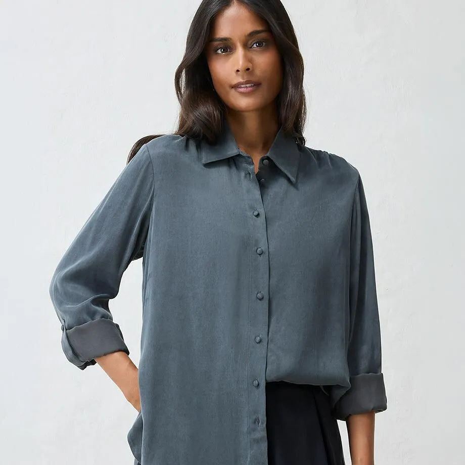 La donna indossa un'elegante camicetta grigio scuro e una semplice gonna nera.