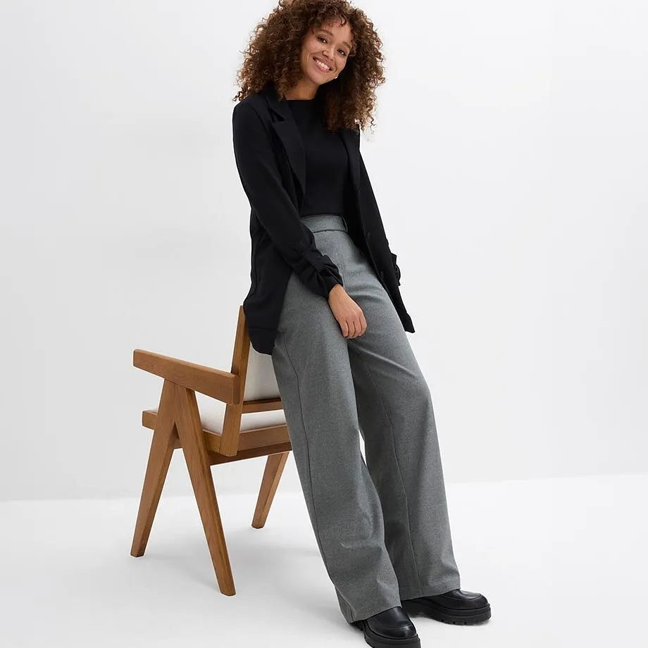 Top nero, blazer, pantaloni larghi grigi e scarpe nere massicce.