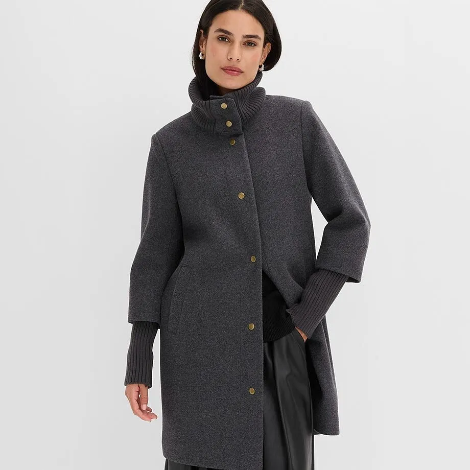 Elegante cappotto corto grigio con collo alto, bottoni dorati e maniche a costine.