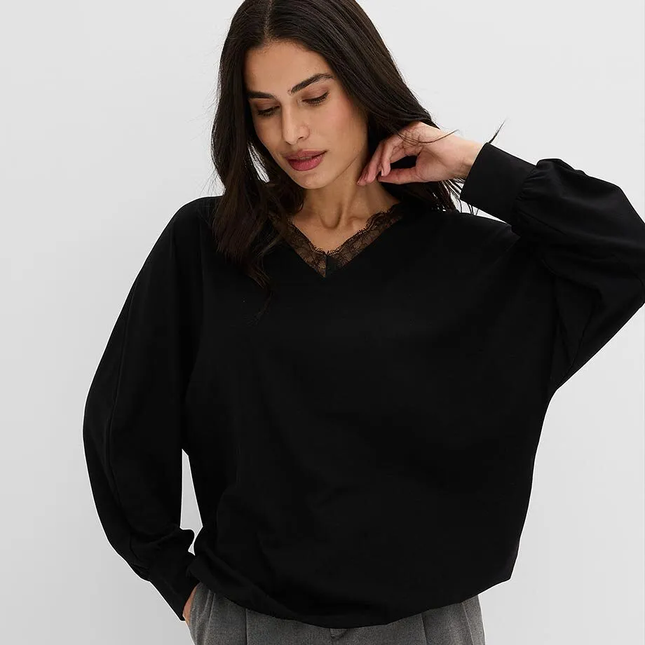Elegante maglione nero con bordi in pizzo sullo scollo e comodi pantaloni grigi.