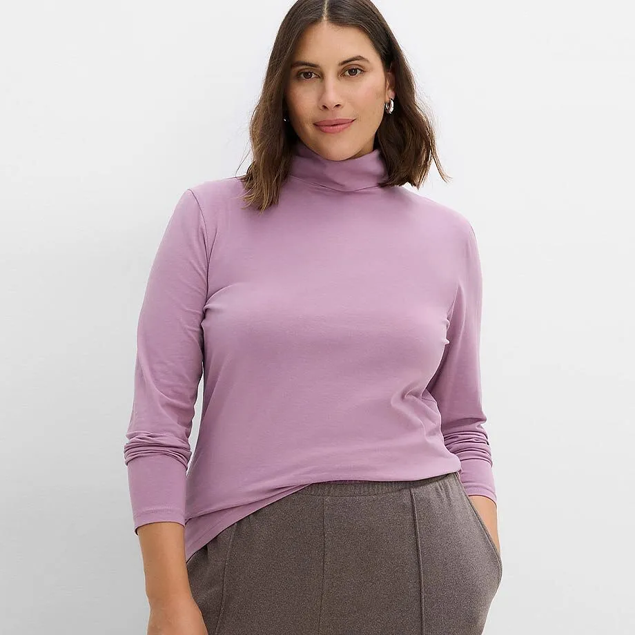 Elegante maglia a collo alto viola abbinata a morbidi pantaloni marrone scuro.