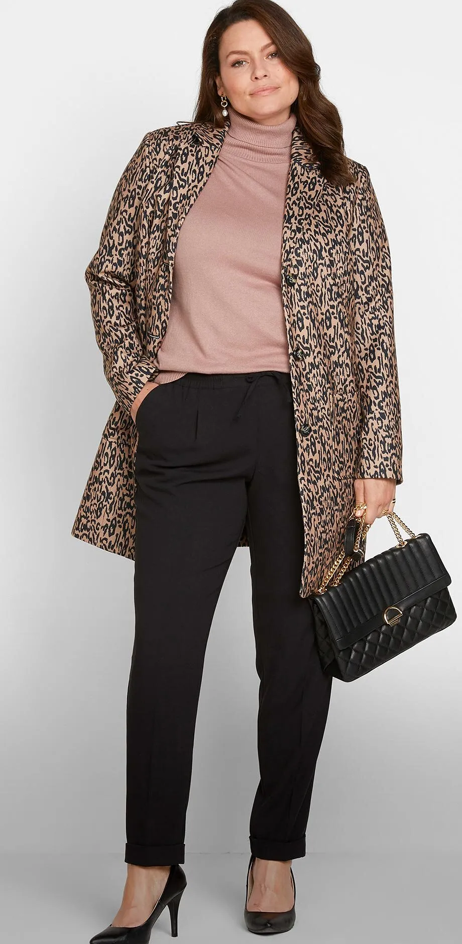 Un elegante cappotto a fantasia, un maglione rosa, pantaloni neri, d&eacute;collet&eacute; e una borsetta.