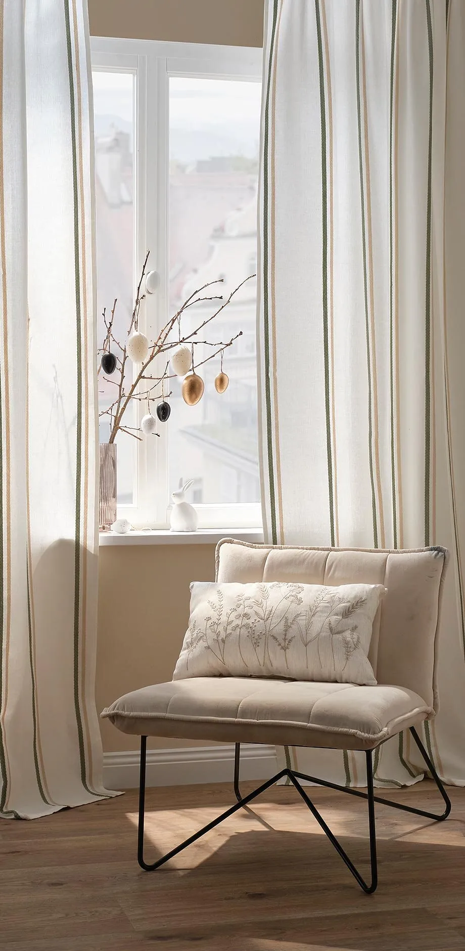 Eleganti tende color crema e una comoda poltrona.