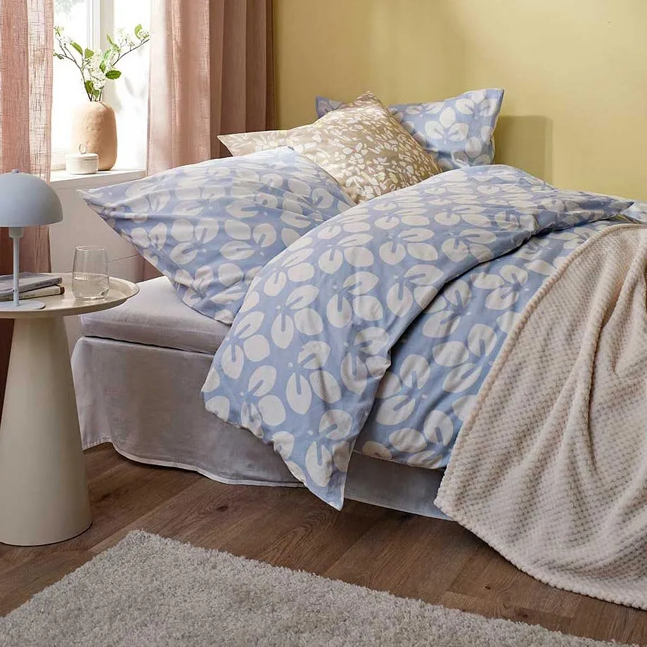 Biancheria da letto blu e bianca, coperta beige e tende rosa.