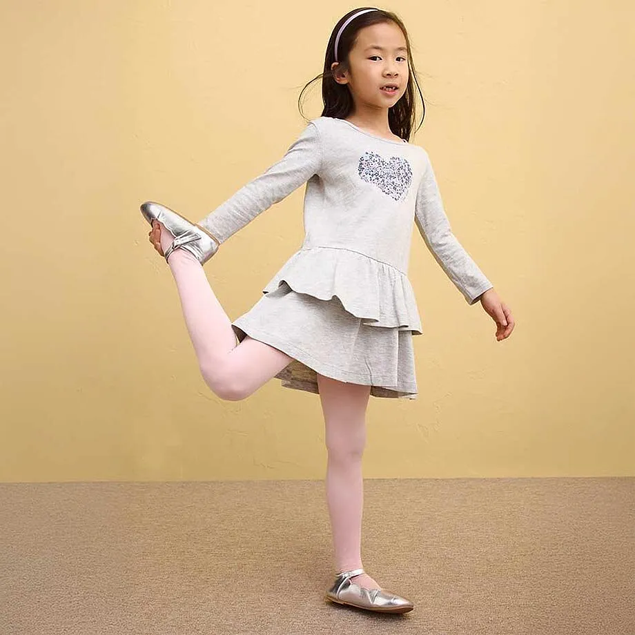 Una bambina indossa un vestito grigio con volant e leggings rosa.