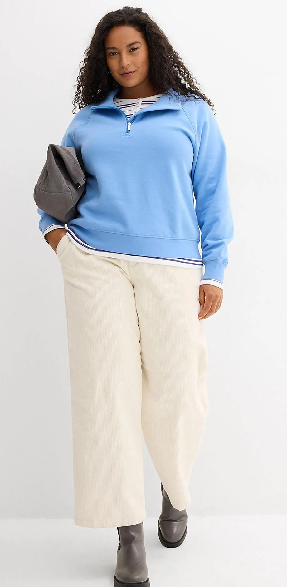 Maglione azzurro e pantaloni larghi color crema.