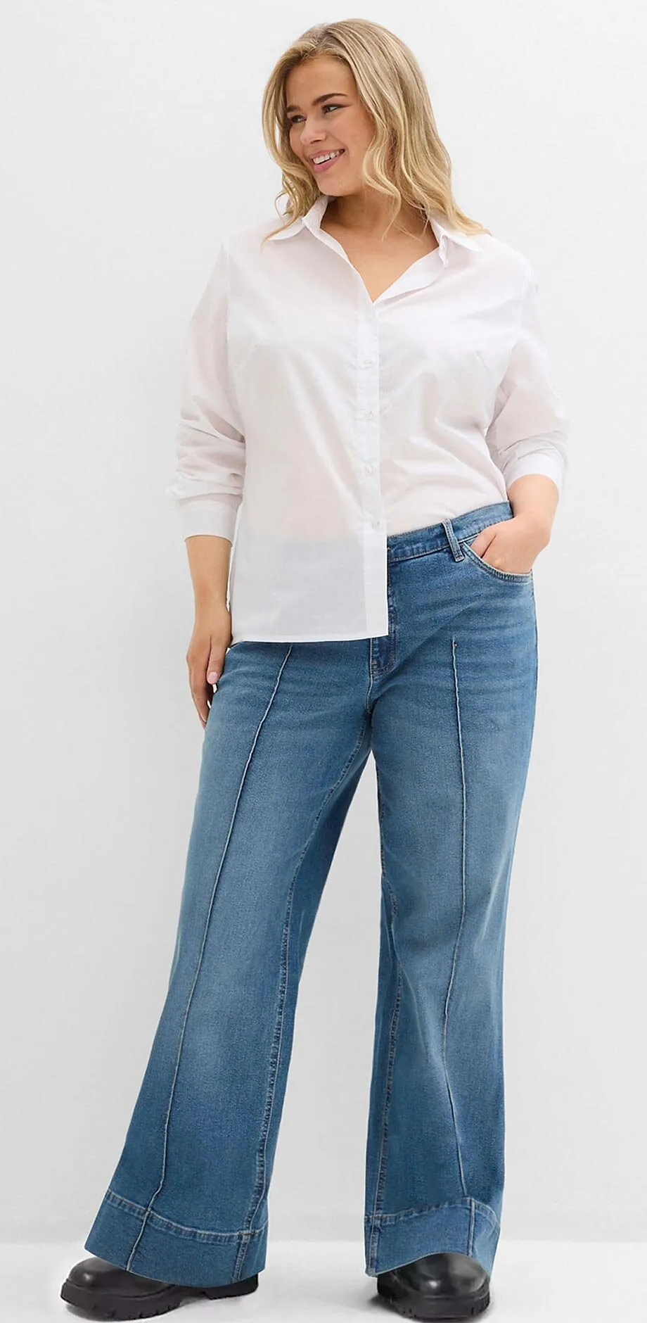 Camicia bianca abbinata a jeans larghi e scarpe nere.