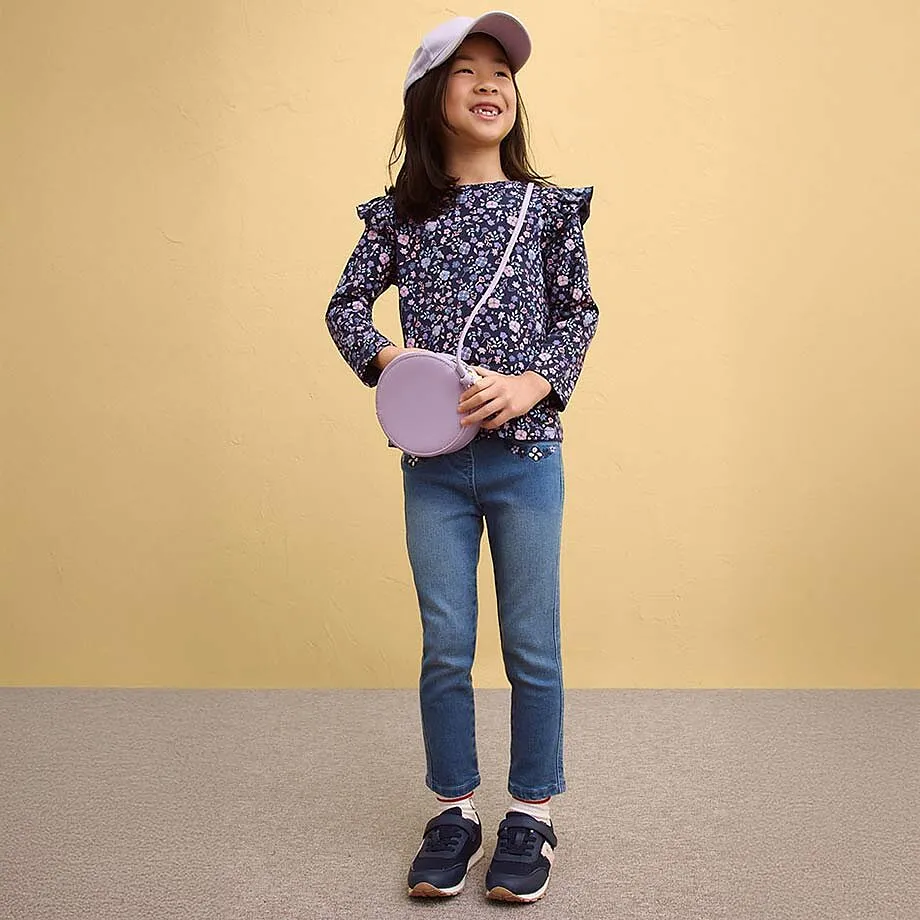 Blusa floreale con volant abbinata a jeans e sneakers.