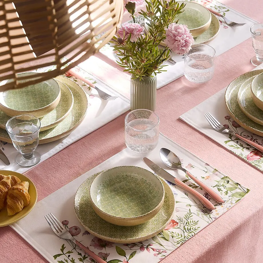 Una tovaglia color rosa impreziosisce la tavola apparecchiata.