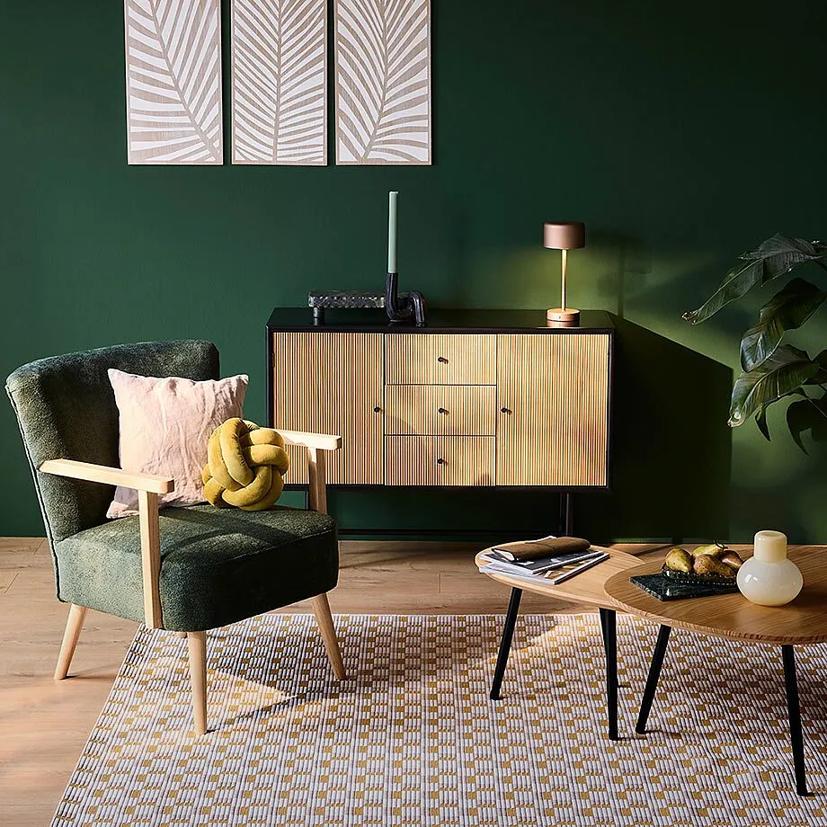 Comoda poltrona con velluto verde, calde tonalit&agrave; del legno e morbidi tessuti.